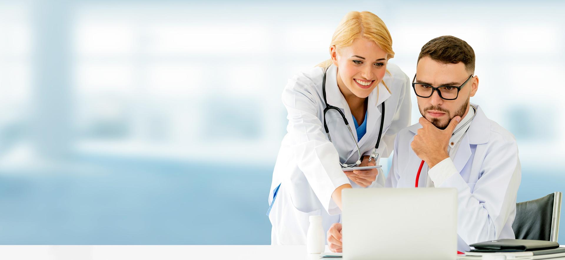 Pracownica medyczna wskazująca ekran komputera pracownikowi medycznemu