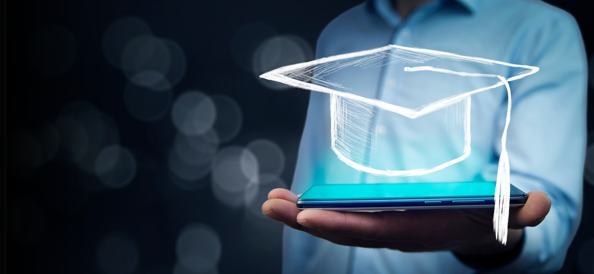 Man holding tablet with graduation cap on bokeh background