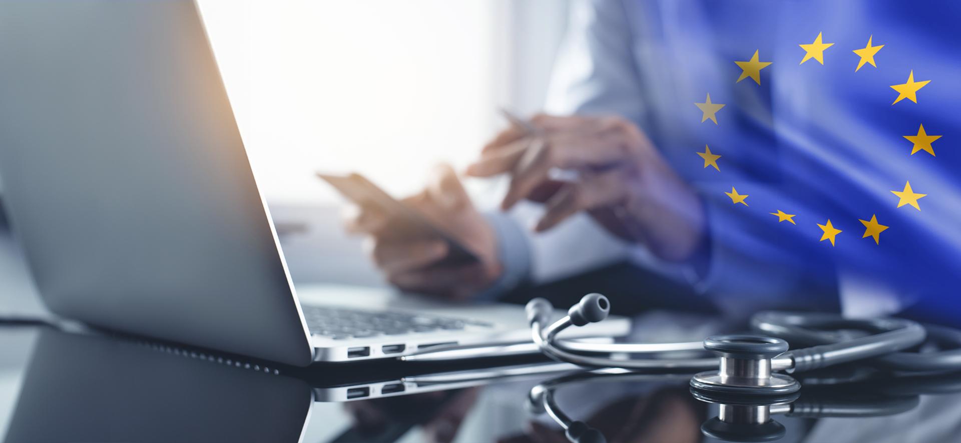 laptop, obok dłoni mężczyzny trzymające telefon