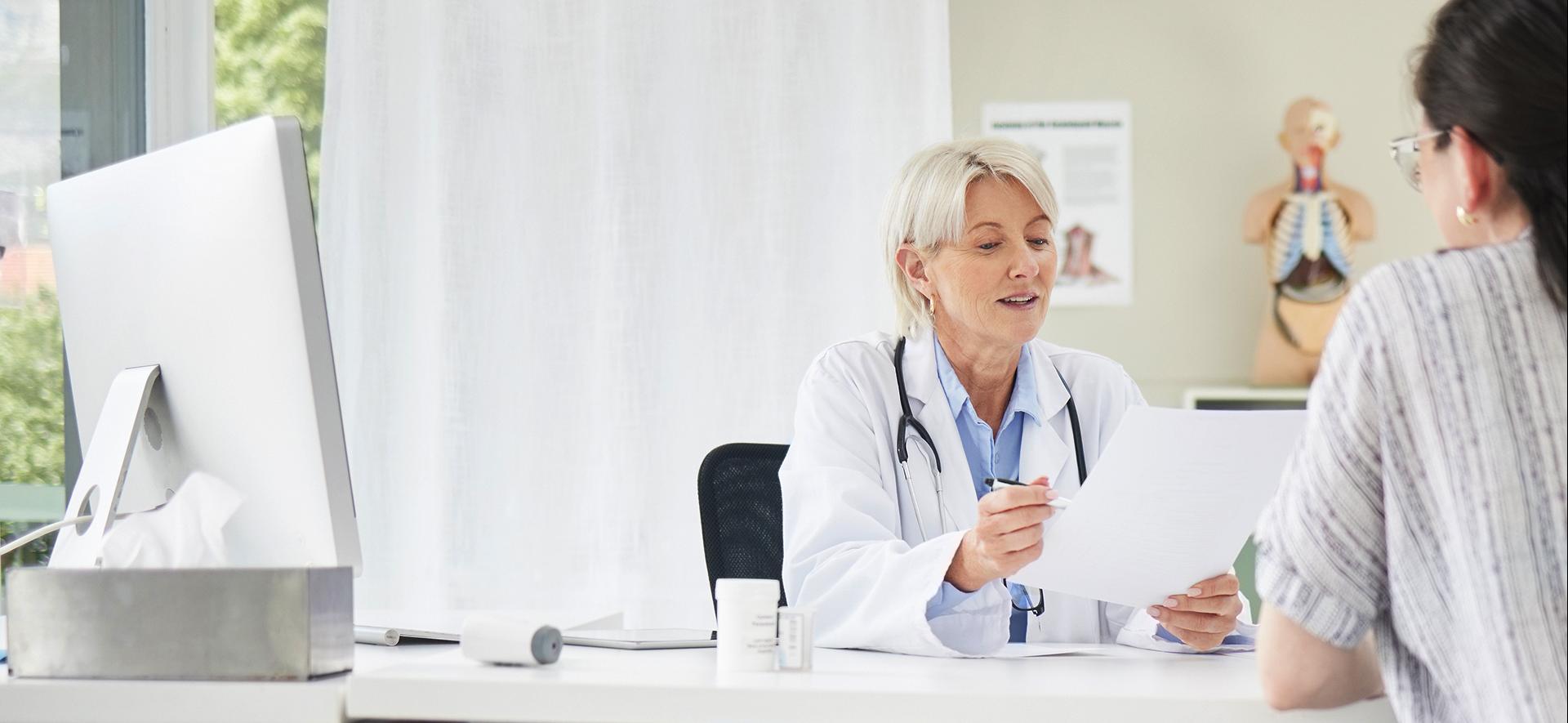 lekarka rozmawiająca z pacjentem przy biurku
