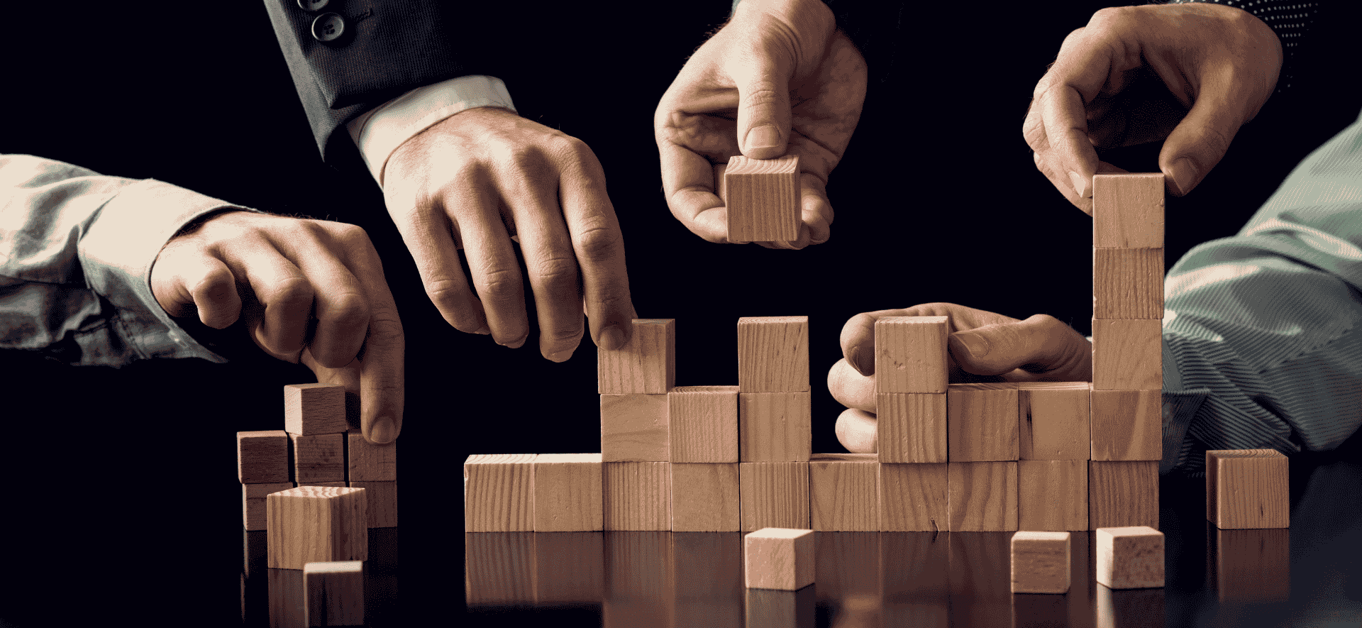 ręce współpracujące nad budową budowli z drewnianych