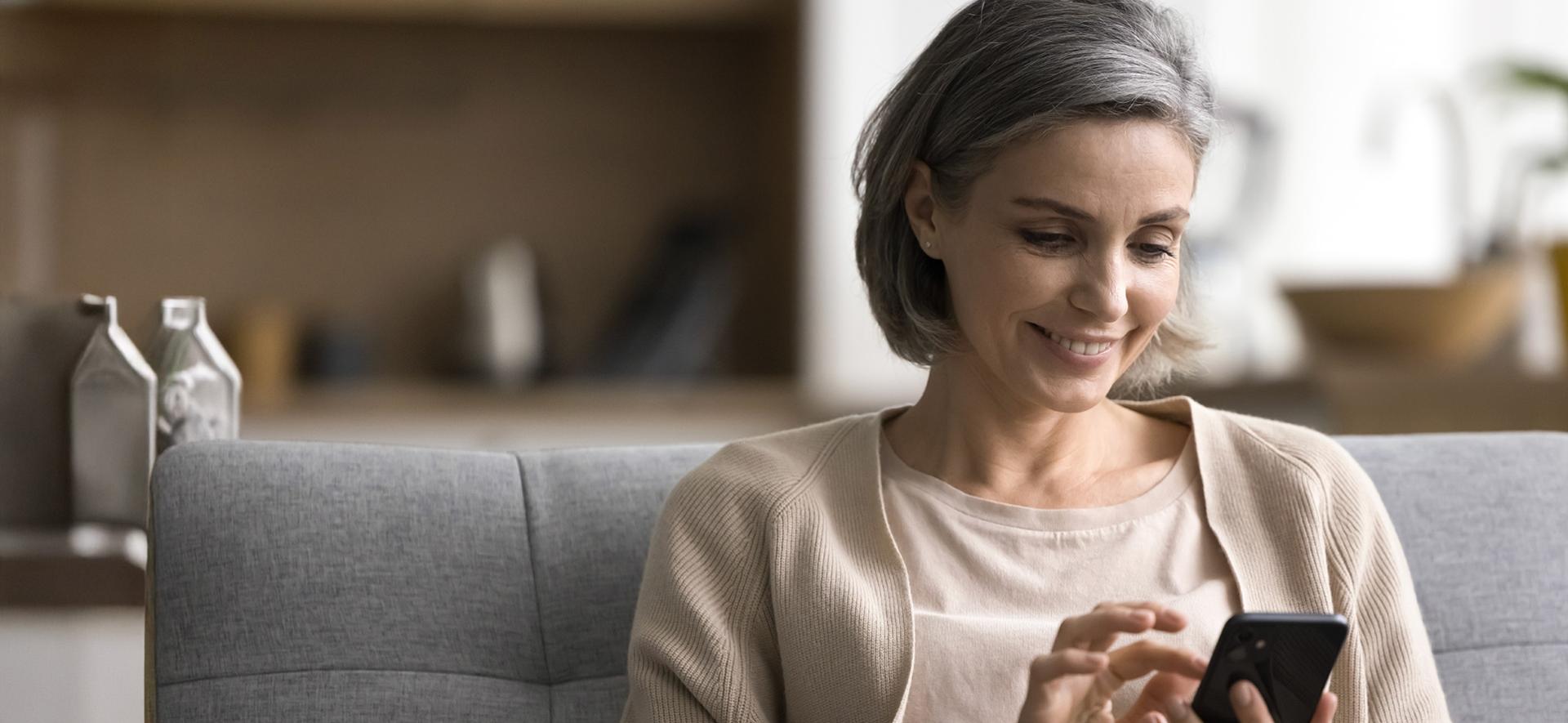 Kobieta w wieku powyżej 40 lat patrząca w ekran telefonu.