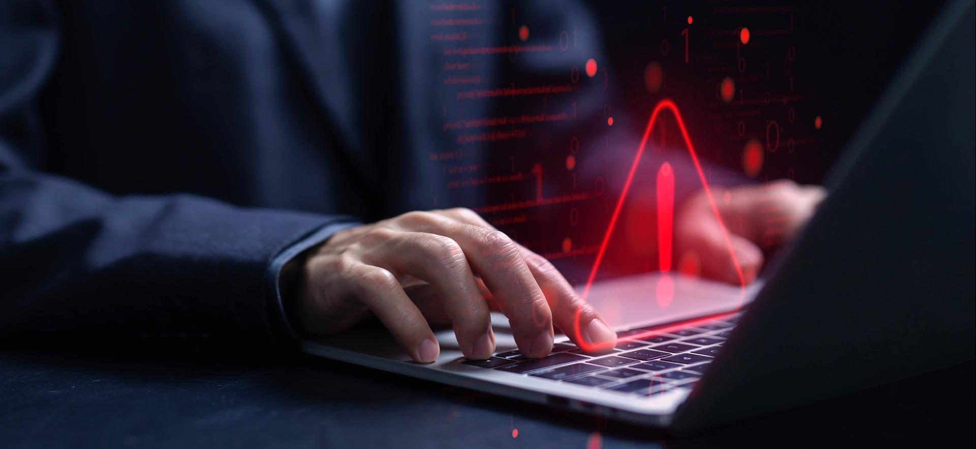 czerwony trójkąt z wykrzyknikiem w środku unosi się nad klawiaturą laptopa