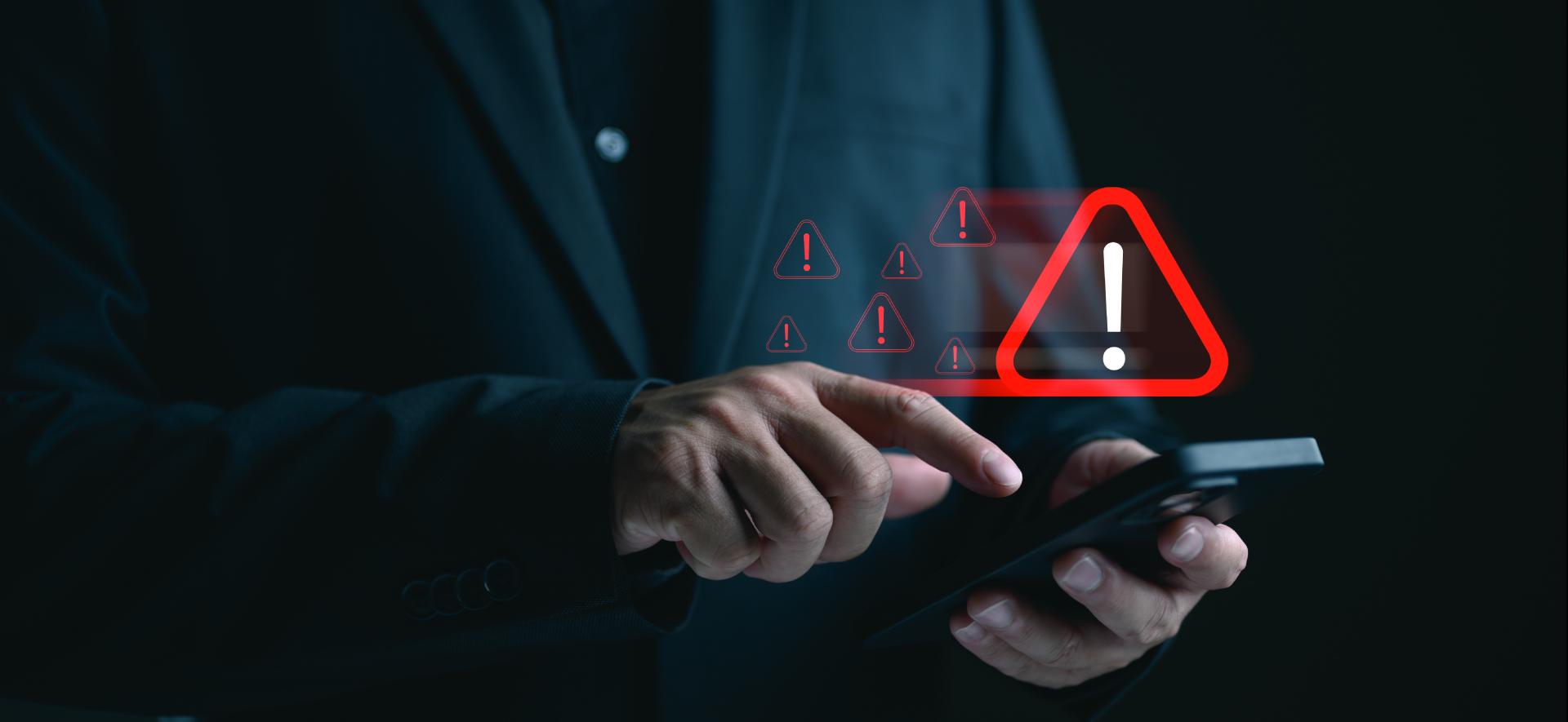 czerwony trójkąt z wykrzyknikiem w środku unosi się nad klawiaturą laptopa