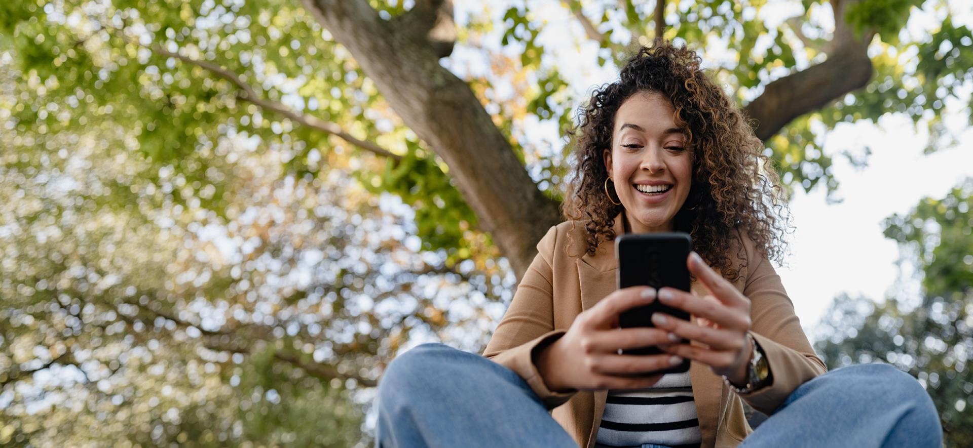 Uśmiechnięta kobieta patrzy na ekran smartfona