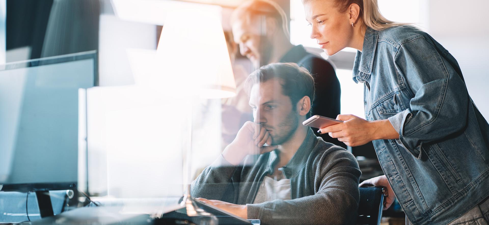 Grupa pracowników omawiająca zadanie przed laptopem