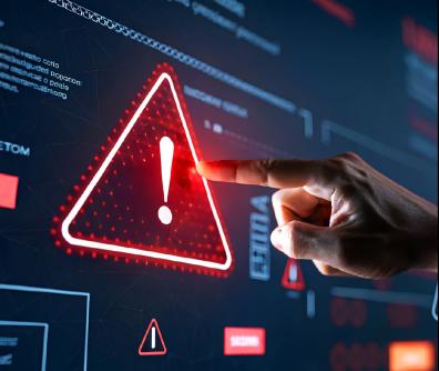 czerwony trójkąt z wykrzyknikiem w środku unosi się nad klawiaturą laptopa