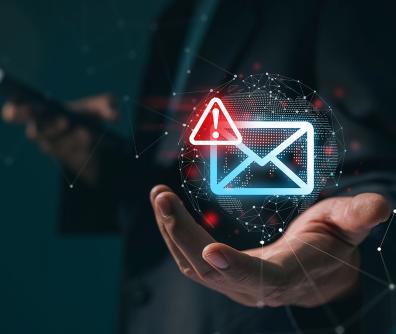 nad ręką unosi się niebieski neon w kształcie koperty z czerwonym trójkątem z wykrzyknikiem w rogu