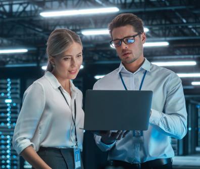 kobieta i mężczyzna ubrani w białe koszule patrzą na ekran laptopa