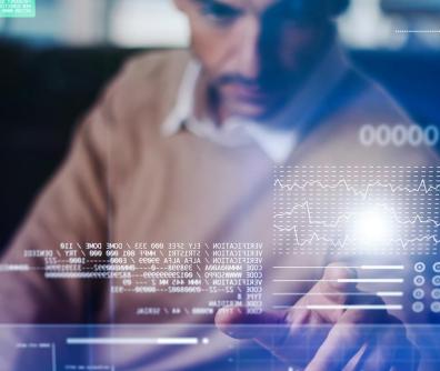 na pierwszym planie napisy i ikony informatyczne a na drugim planie mężczyzna korzystający z komputera