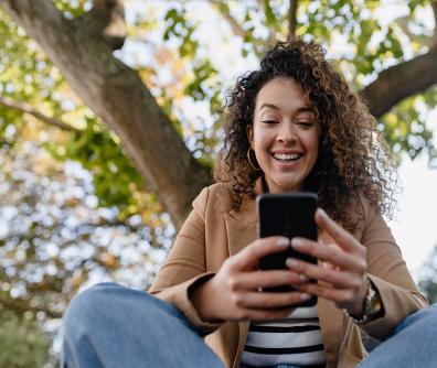 Uśmiechnięta kobieta patrzy na ekran smartfona