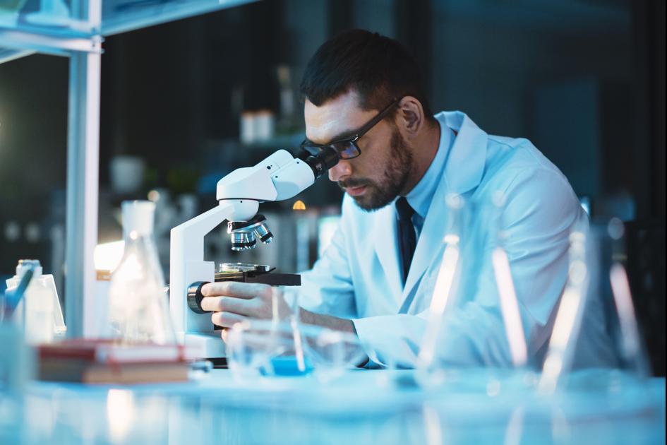 Diagnosta laboratoryjny oglądający próbkę przez mikroskop