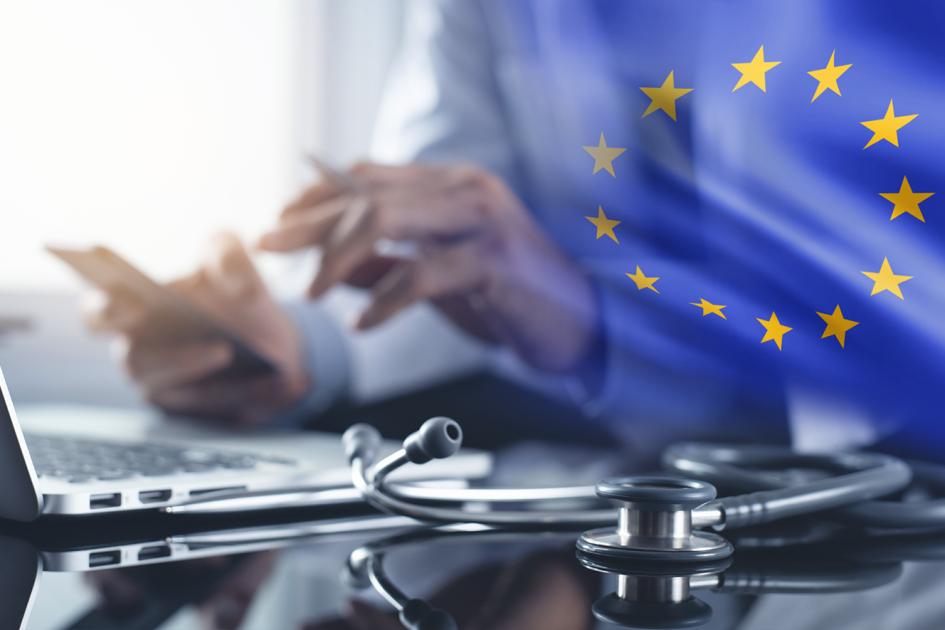 laptop, obok dłoni mężczyzny trzymające telefon