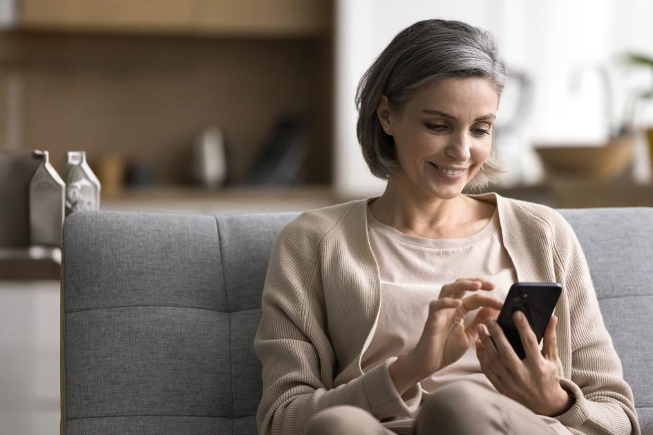 Kobieta w wieku powyżej 40 lat patrząca w ekran telefonu.