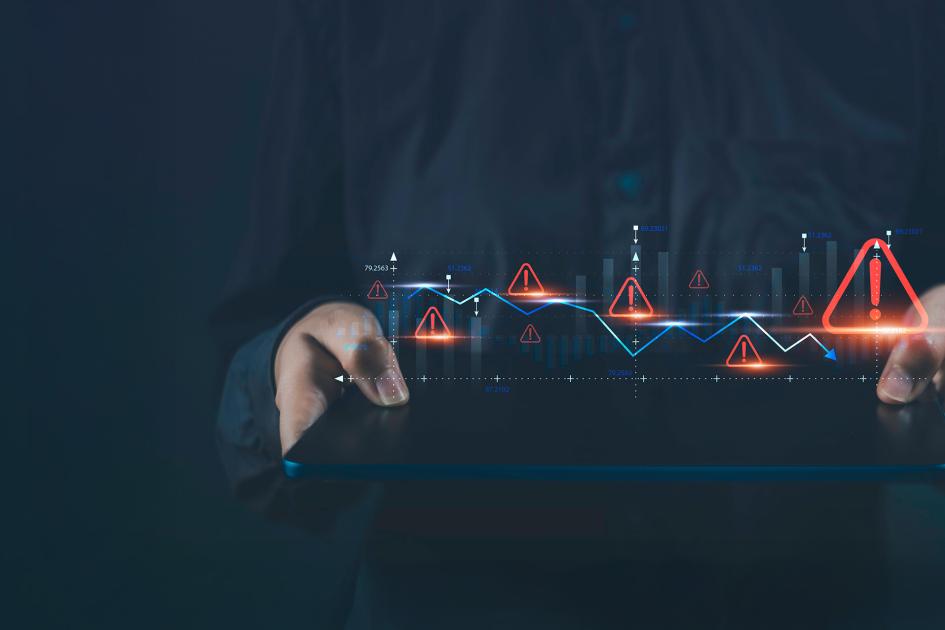 ręce trzymają poziomo tablet, a nad nim unoszą się ikony wykrzykników w trójkątach