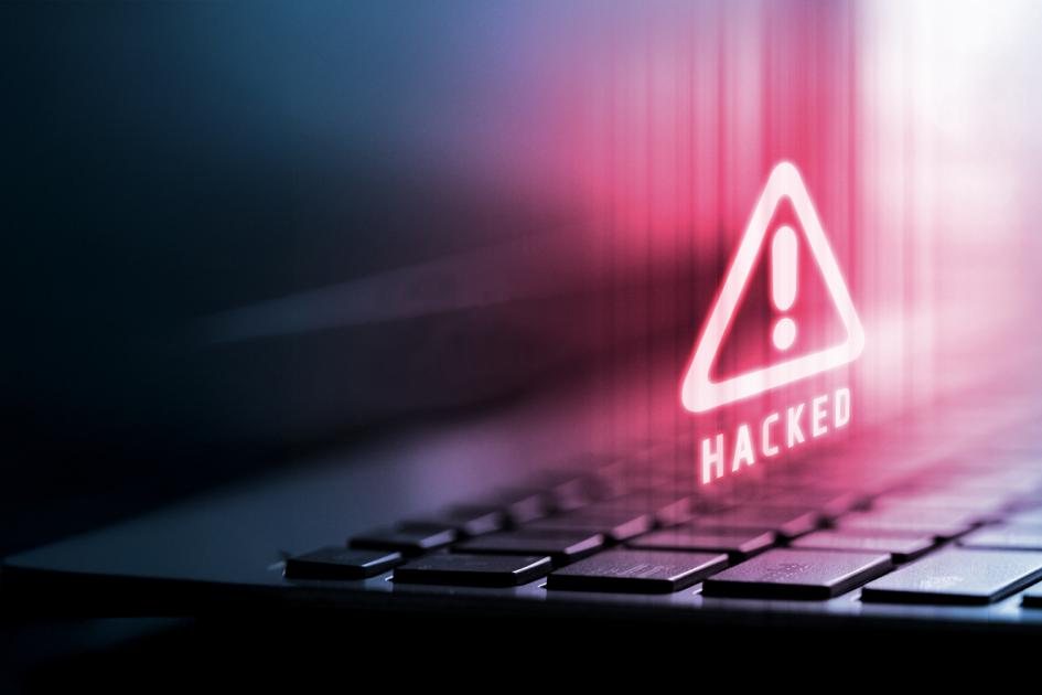 czerwony trójkąt z wykrzyknikiem w środku unosi się nad klawiaturą laptopa