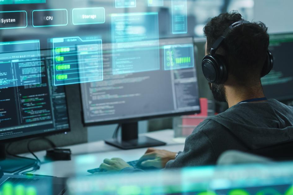 osoba siedzi tyłem przed ekranami