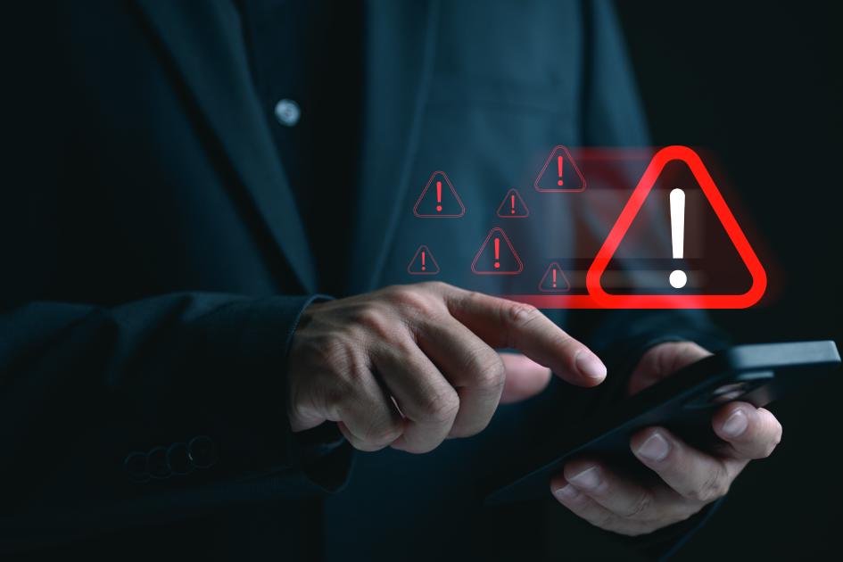 czerwony trójkąt z wykrzyknikiem w środku unosi się nad klawiaturą laptopa