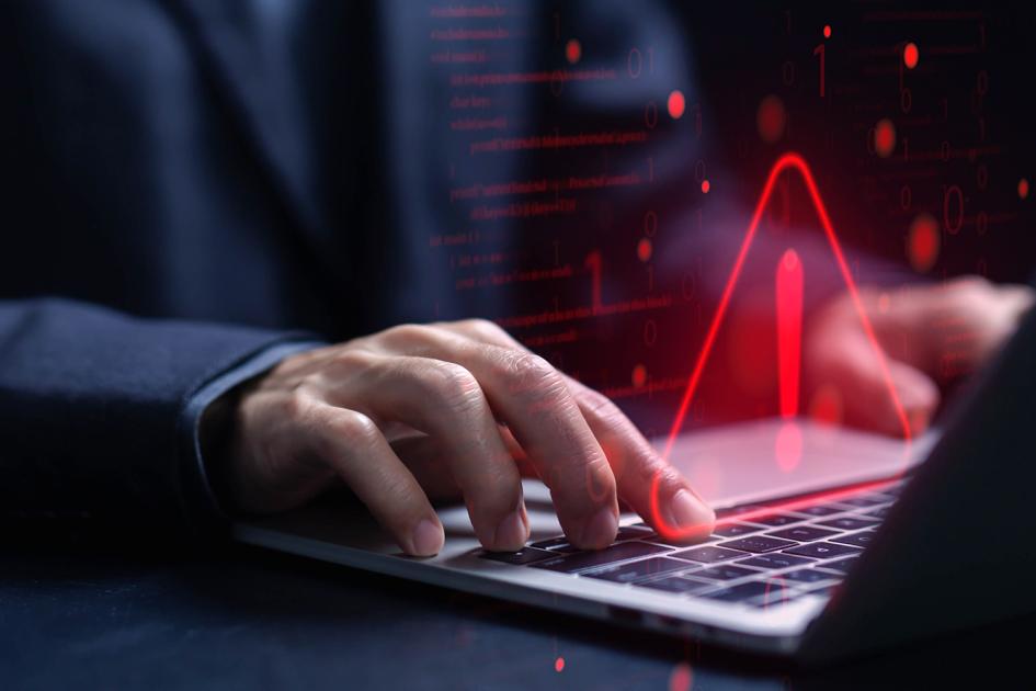 czerwony trójkąt z wykrzyknikiem w środku unosi się nad klawiaturą laptopa