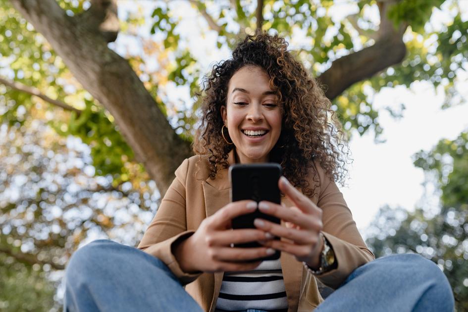 Uśmiechnięta kobieta patrzy na ekran smartfona