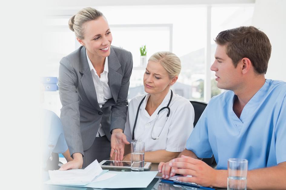 Grupa osób stojąca nad stołem, na którym rozłożone są dokumenty